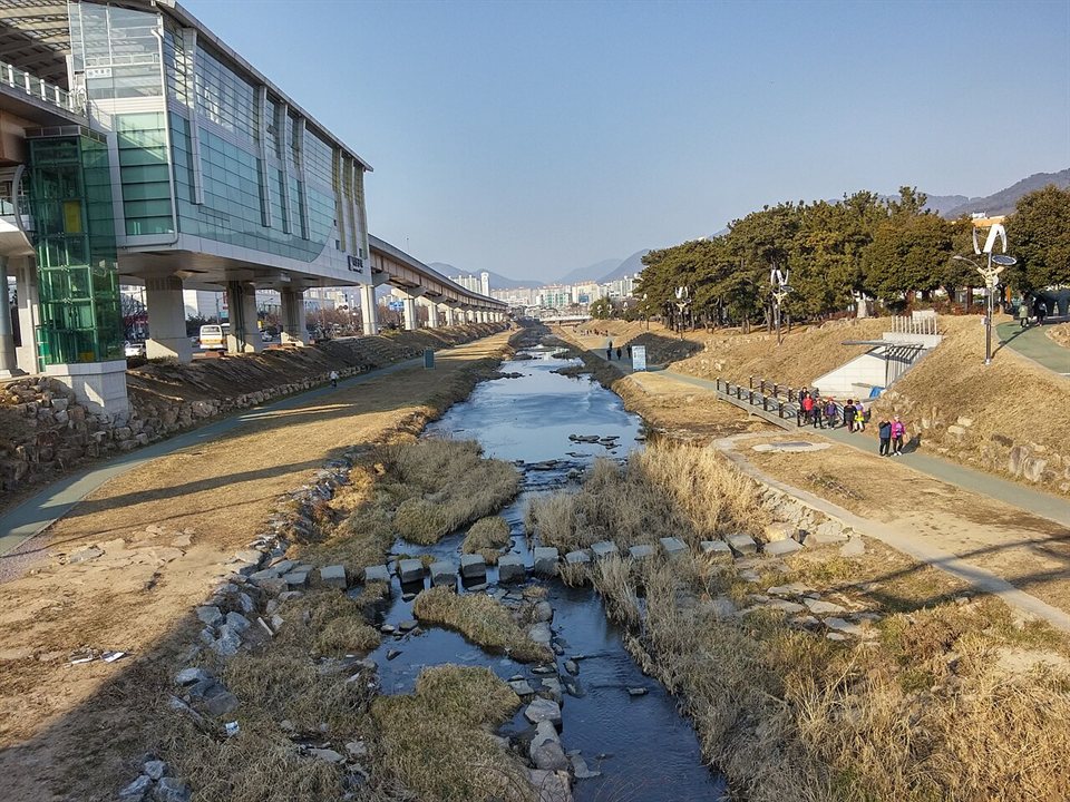 부산김해경전철 고가 선로와 나란히 흐르는 김해 해반천 산책로 — 인제대 2027 정시
