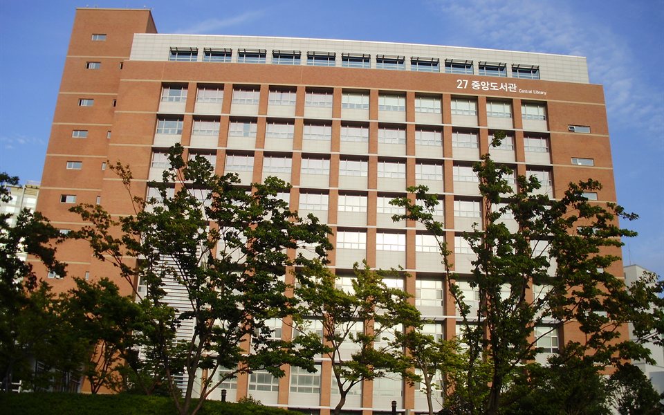 나무 사이로 보이는 경성대학교 중앙도서관 건물 — 경성대 2027 정시